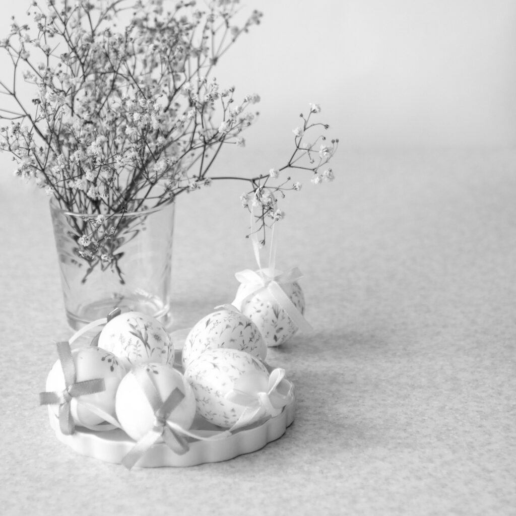 Easter egg decoration with floral pattern and ribbon beside vase of delicate baby s breath